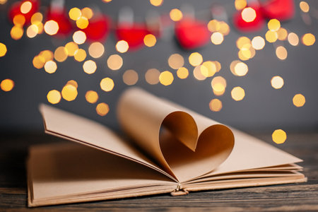 Heart made from book sheets in lights, love and valentine concept on a wooden tableの写真素材