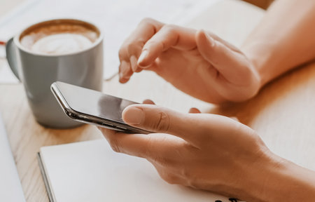 Man writes business information in notebook at workplace in office with smartphoneの写真素材