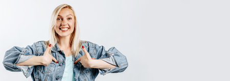 Beautiful young girl pointing with fingers on gray isolated backgroundの写真素材
