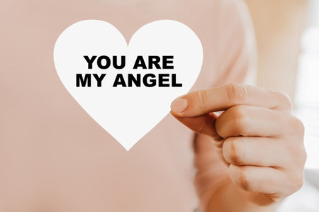 Man holding a love card in the shape of a heart with You are my angelの写真素材