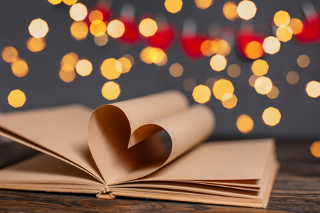 Heart made from book sheets in lights, love and valentine concept on a wooden tableの写真素材