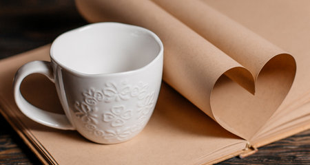 Heart made from book sheets with a cup, love and valentine concept on a wooden tableの写真素材