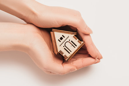 Hand holds house miniature model on white background. Investment, real estate, home, housingの写真素材