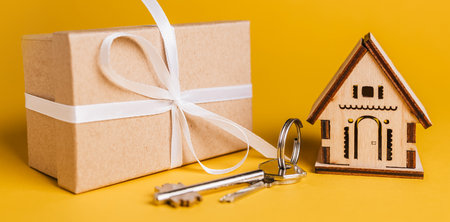 House miniature model, gift and keys on a yellow background. Investment, real estate, home, housingの写真素材