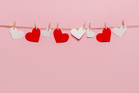 white and red heart pin on a rope on isolated pink background, love and valentine conceptの写真素材