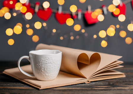 Heart made from book sheets with a cup, love and valentine concept on a wooden tableの写真素材