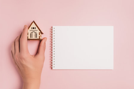 Hand holds house miniature model with blank background on a pink background. Investment, real estate, home, housingの写真素材