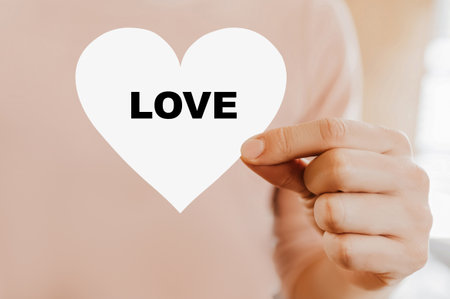 Man holding a love card in the shape of a heart with loveの写真素材