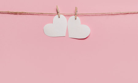 white heart pin on a rope on isolated pink background, love and valentine conceptの写真素材