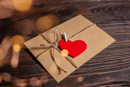 Love letter with a heart on a background of lights, love and valentine concept on a wooden tableの写真素材