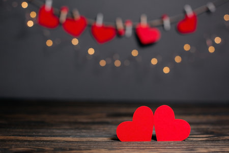 pair of red hearts on lights background, love and valentine concept on a wooden tableの写真素材