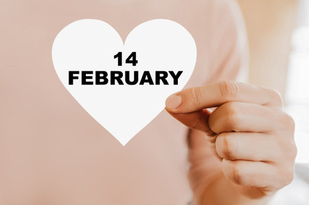 Man holding a love card in the shape of a heart with 14 februaryの写真素材