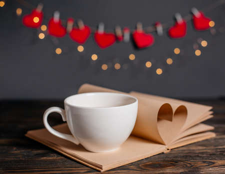 Heart made from book sheets with a cup, love and valentine concept on a wooden tableの写真素材