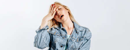 Beautiful young girl unhappy frown and sigh on gray isolated backgroundの写真素材