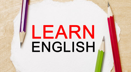 Learn ENGLISHon a white notepad with pencils on a wooden background. Business conceptの写真素材