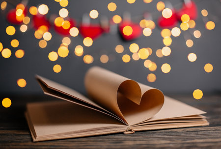 Heart made from book sheets in lights, love and valentine concept on a wooden tableの写真素材