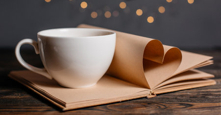 Heart made from book sheets with a cup, love and valentine concept on a wooden tableの写真素材