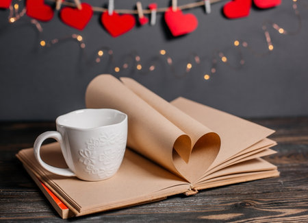 Heart made from book sheets with a cup, love and valentine concept on a wooden tableの写真素材