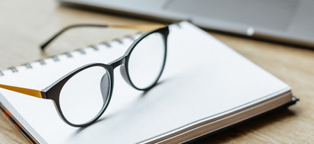 Glasses at the workplace in the office near the laptop and notepad. Business hoursの写真素材