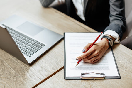 Young girl office worker or business lady signs documents. Concentrated businesswoman working with papers. Business conceptの写真素材