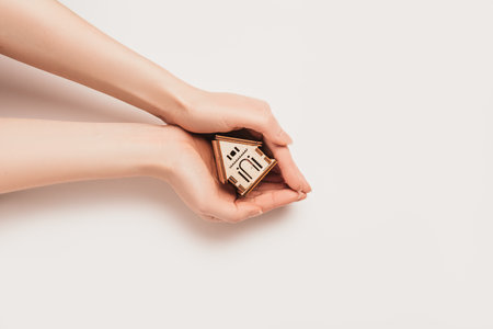Hand holds house miniature model on white background. Investment, real estate, home, housingの写真素材