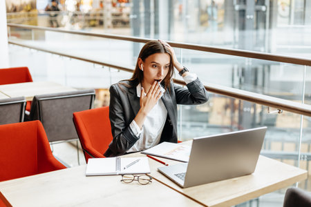 Girl works on a laptop in the workplace. Businesswoman is shocked by the crisis. Successful woman creates a startup and makes decisions.の写真素材