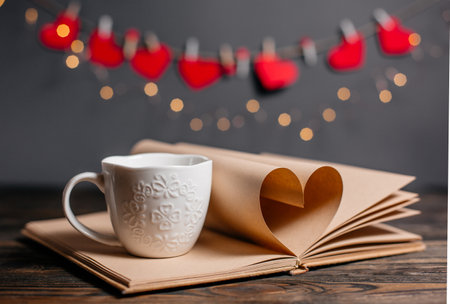 Heart made from book sheets with a cup, love and valentine concept on a wooden tableの写真素材