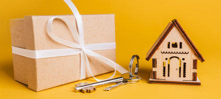 House miniature model, gift and keys on a yellow background. Investment, real estate, home, housingの写真素材