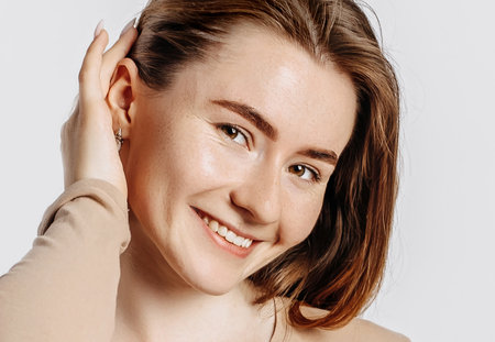 Beautiful young girl smiling and posing looking at the camera on a white isolated background. Positive brunette woman. Kind look. Beauty face.の写真素材