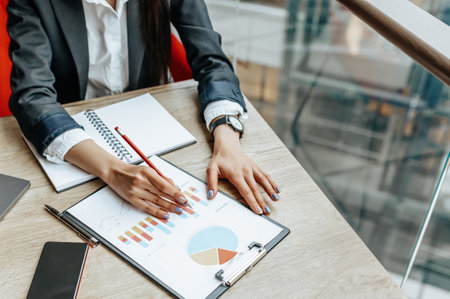 Business woman checks charts and refreshes financial progress. The girl analyzes the business model in the workplace.の写真素材