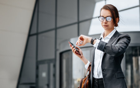 A business woman checks the time in the city during a working day waiting for a meeting. Discipline and timing. An employee goes towards a corporate meeting.の写真素材