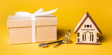 House miniature model, gift and keys on a yellow background. Investment, real estate, home, housingの写真素材