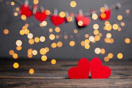 pair of red hearts on lights background, love and valentine concept on a wooden tableの写真素材