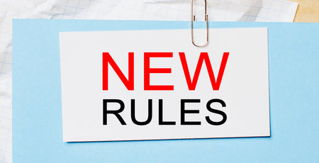 Text new rules on a white card on a blue background. Business conceptの写真素材