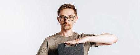 Young handsome man in glasses holding folder for papers with documents, student, worker looks data information, posing for photo isolated on gray background.の写真素材