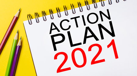 ACTION PLAN 2021 on a white notepad with pencils on a yellow background. Business conceptの写真素材