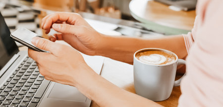Happy business man sitting at cafeteria with laptop and smartphone. Businessman texting on smart phone while sitting in a cafe, working and checking email on computerの写真素材