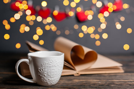 Heart made from book sheets with a cup, love and valentine concept on a wooden tableの写真素材