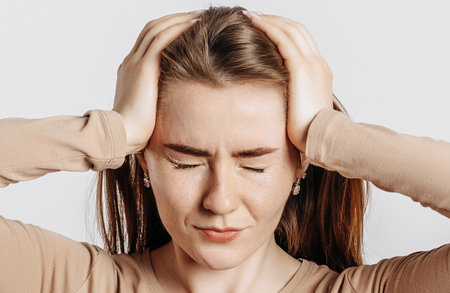 Beautiful young girl posing looking at the camera on a white isolated background. Serious brunette woman ignores covers her ears with her hands and closes her eyes, does not see and does not hearの写真素材