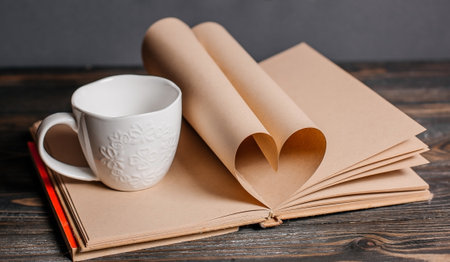 Heart made from book sheets with a cup, love and valentine concept on a wooden tableの写真素材