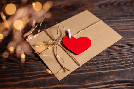 Love letter with a heart on a background of lights, love and valentine concept on a wooden tableの写真素材