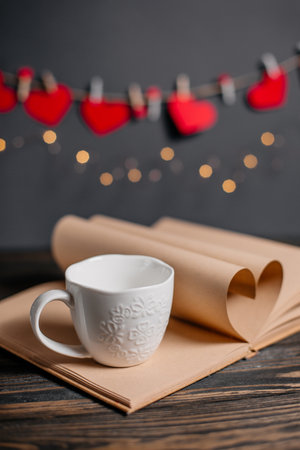 Heart made from book sheets with a cup, love and valentine concept on a wooden tableの写真素材