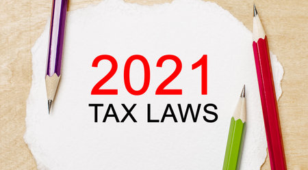 Text 2021 tax laws on a white notepad with pencils on a wooden background. Business conceptの写真素材