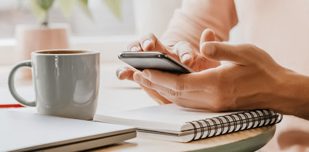 Man writes business information in notebook at workplace in office with smartphone
