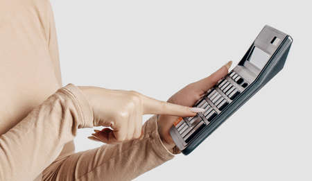 Young business woman holds calculator isolated on gray background. Achieving career wealth business...