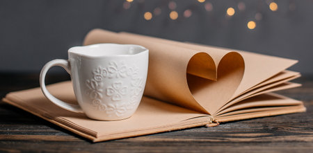 Heart made from book sheets with a cup, love and valentine concept on a wooden tableの写真素材