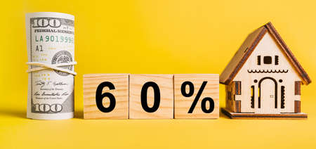 60 interest with house miniature model and money on a yellow background. Investment, real estate, home, housing, earnings, financial conceptの写真素材