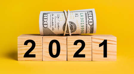 2021 with money on a yellow background. The concept of business, finance, credit, income, savings, investments, exchange, taxの写真素材