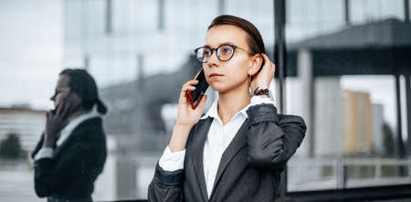 A business woman talking on the phone in the city during a working day waiting for a meeting. Discipline and timing. An employee goes towards a corporate meeting.の写真素材