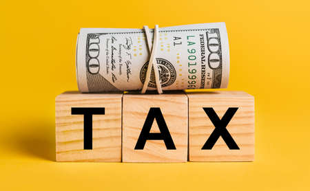 TAX with money on a yellow background. The concept of business, finance, credit, income, savings, investments, exchange, taxの写真素材